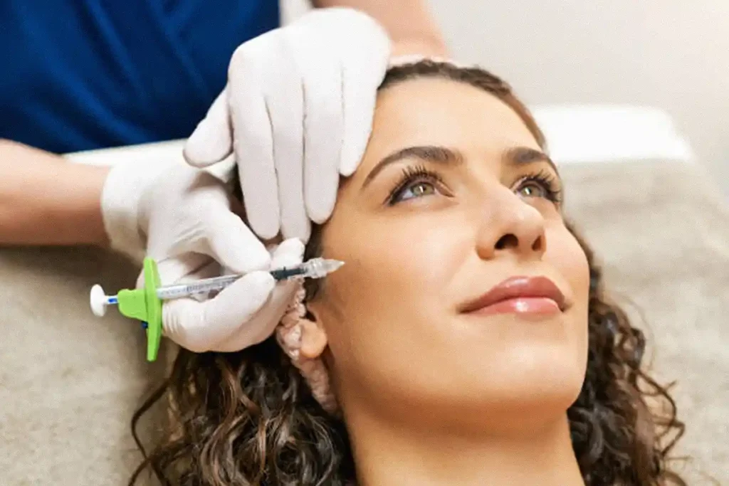 girl smilliing while getting cheek filler treatment